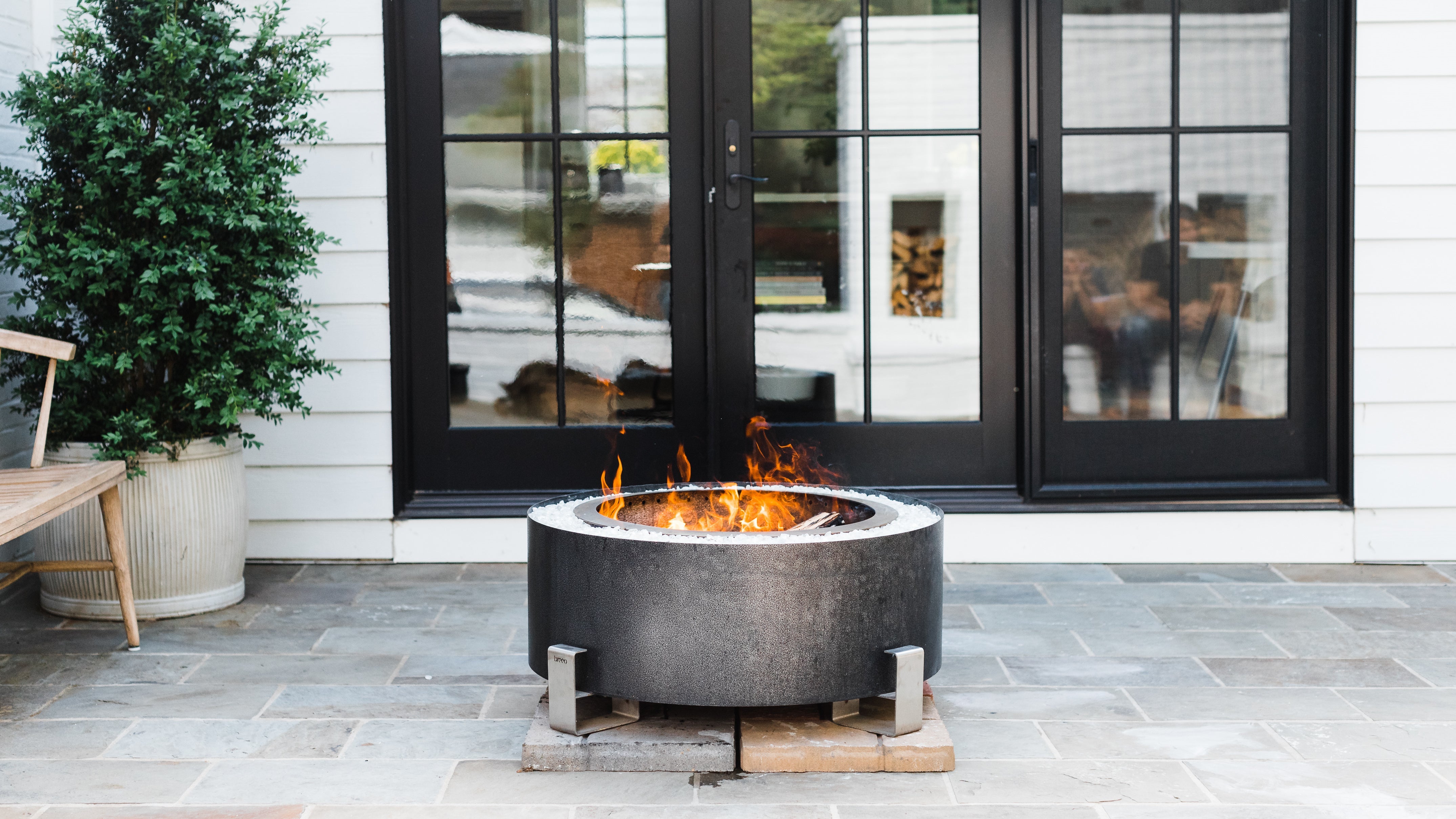 An image of the Luxeve firepit with flames on a patio