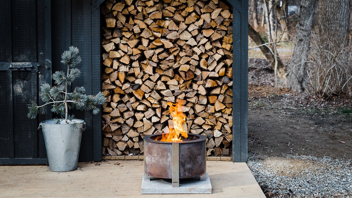 Breeo X Series fire pit in front of a wood stack