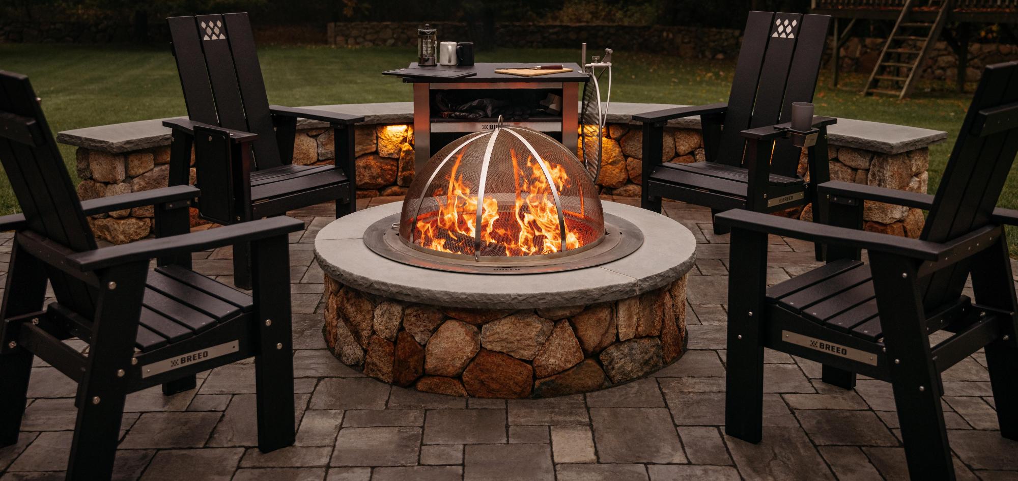 This is an image of the Breeo X Series with Insert ring an Spark Screen installed in a stone surround with X Series Chairs arranged around the firepit