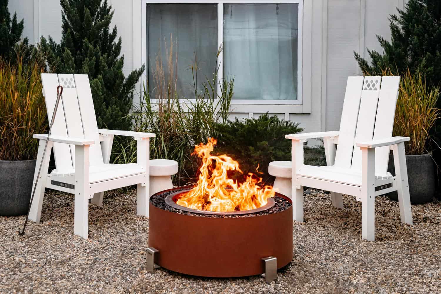 This is an image of two white X Series Chairs with an Earth Rust Luxeve firepit