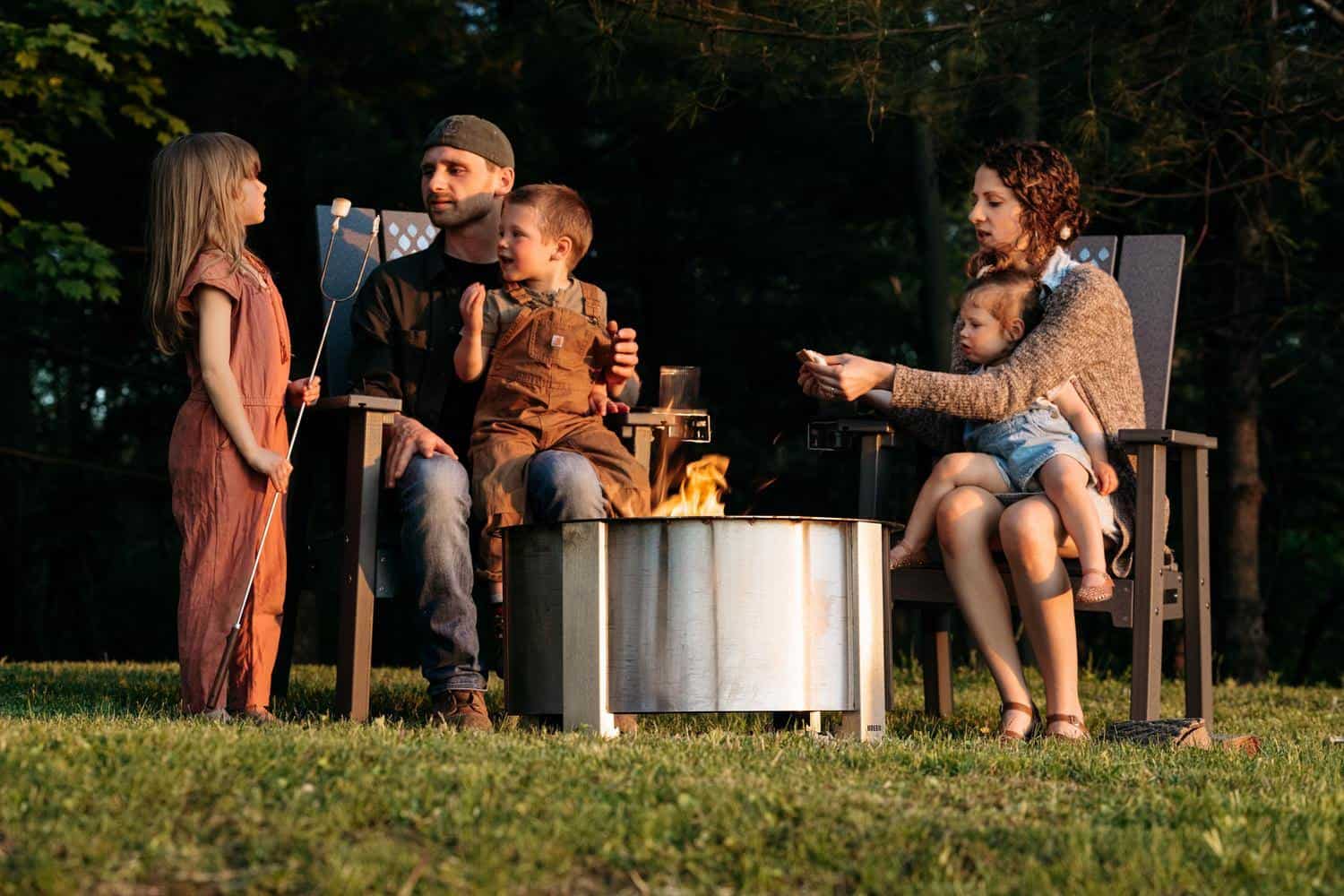 This is an image of a family sitting on Breeo chairs while roasting marshmallows over the fire.