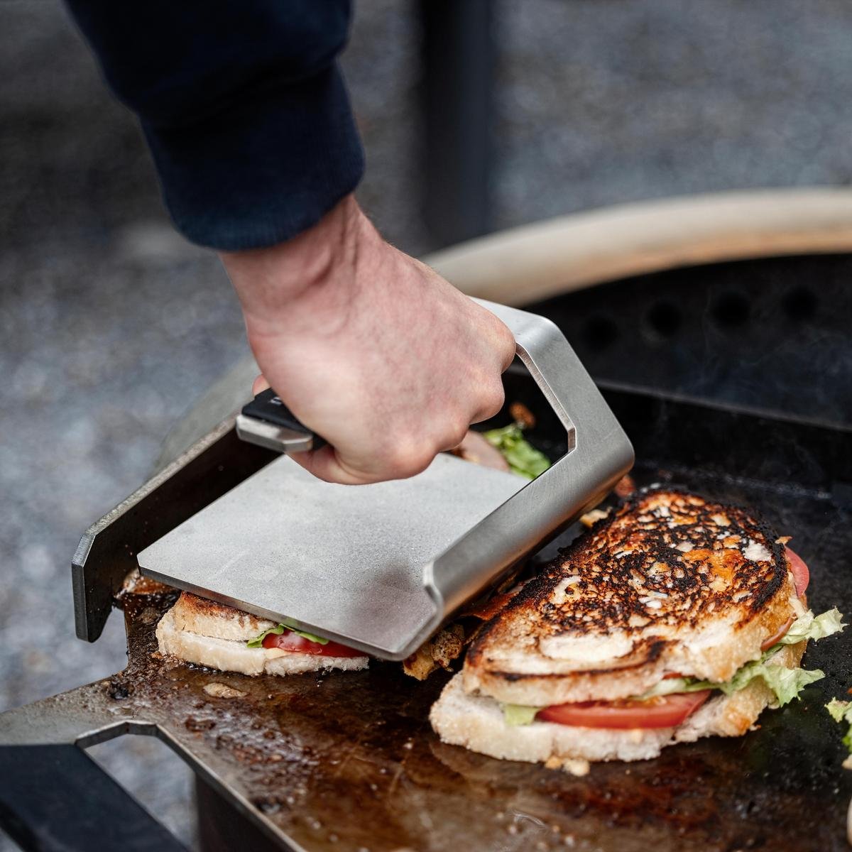 An image of a man pressing paninis on the Flat Top using the Griddle Press