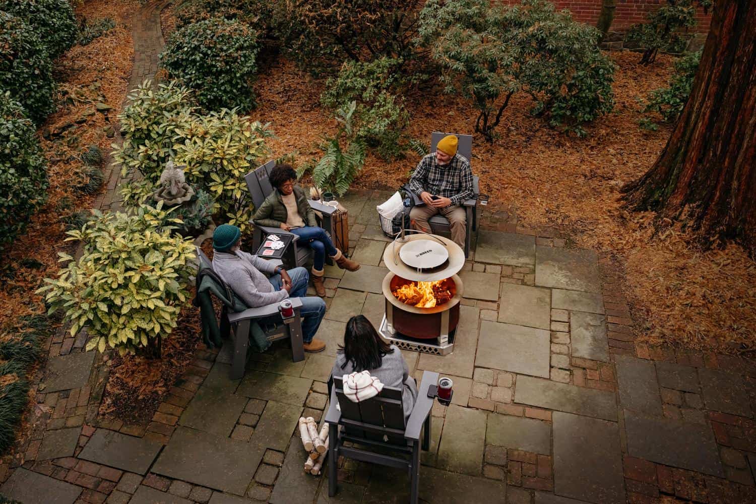 Friends sitting around a fire with a Heat Deflector 24