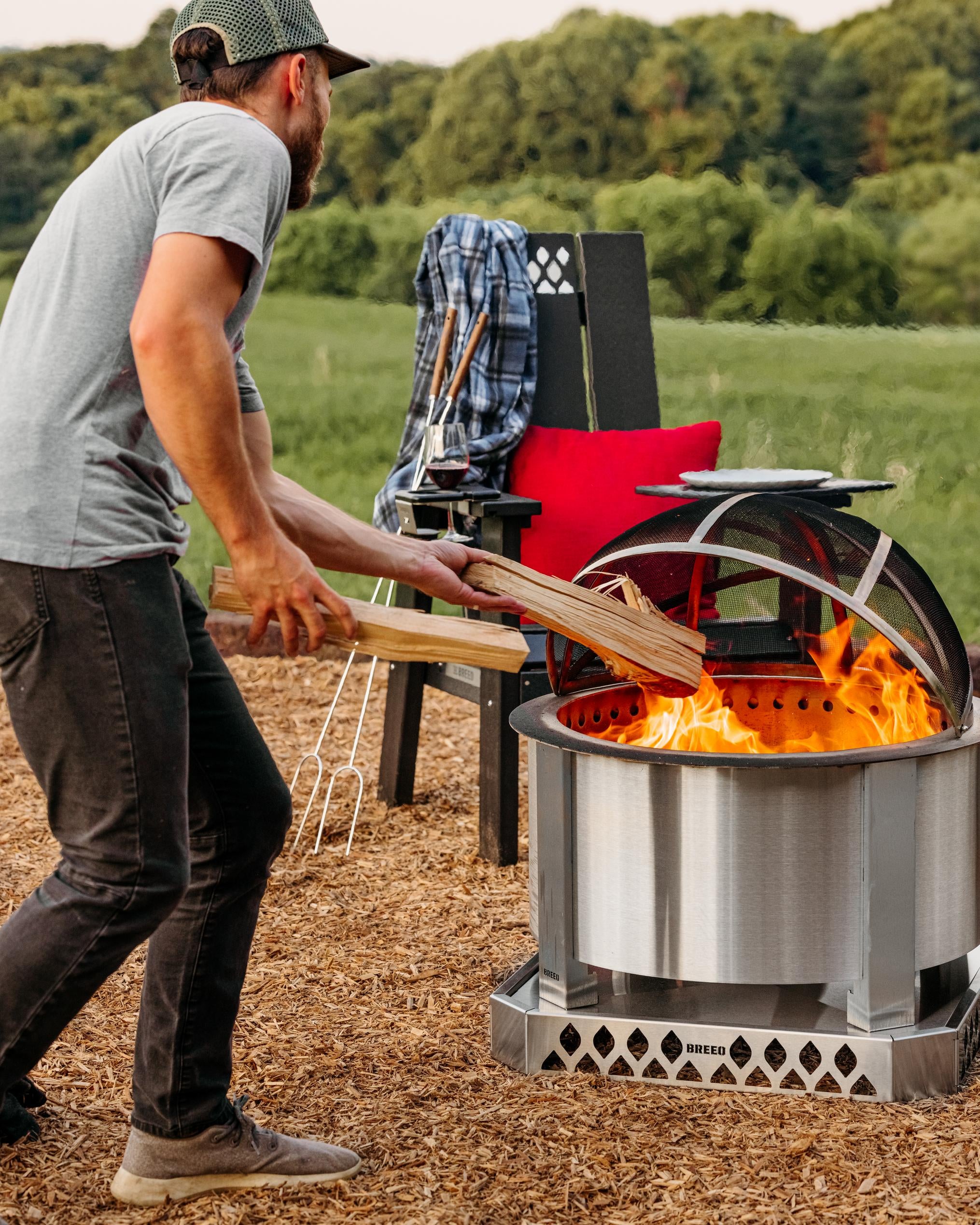 A man throwing logs in the fire with and X19 fire pit