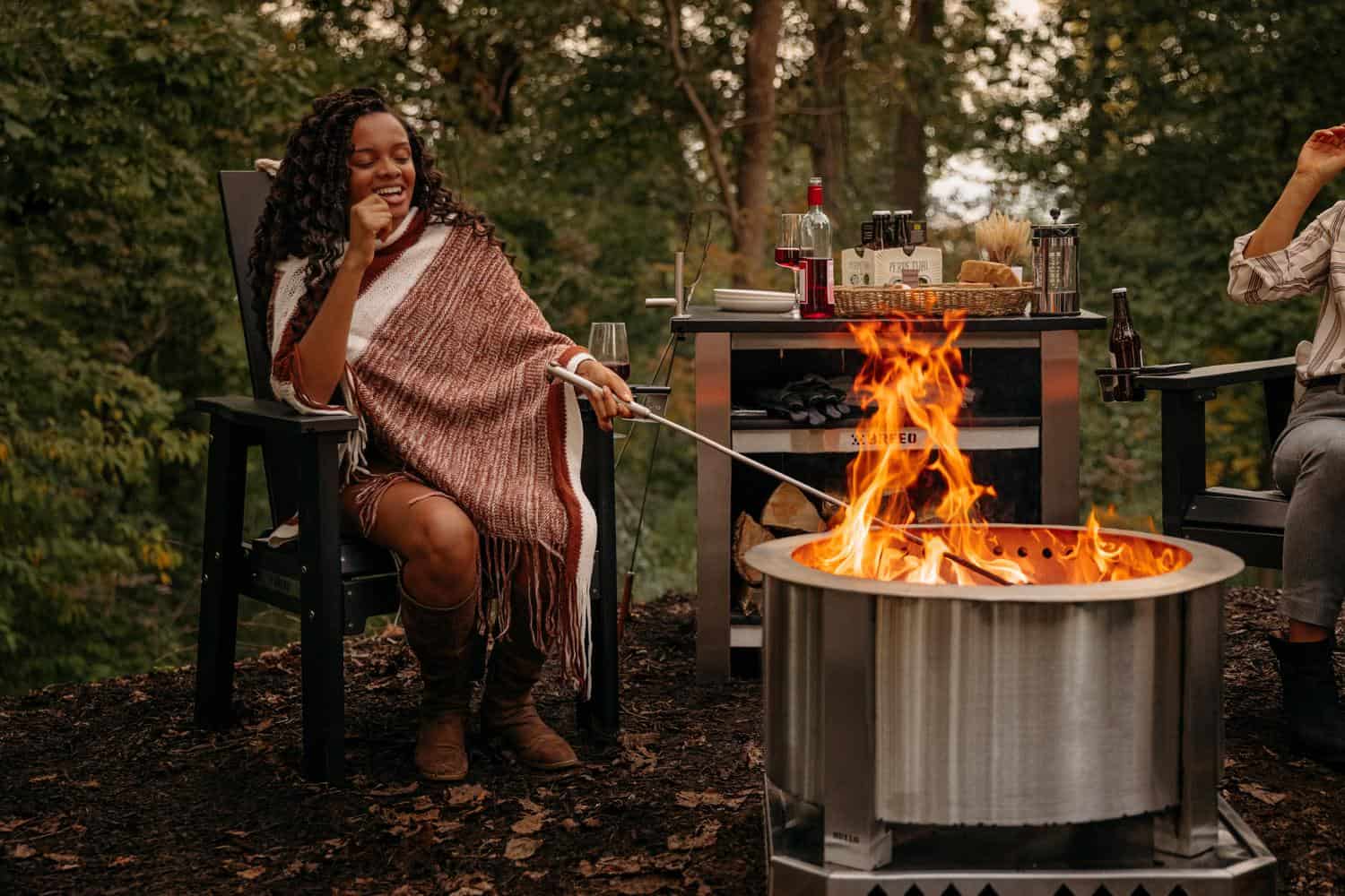 This is an image of a woman stoking the fire using a Breeo 304 Fire Poker