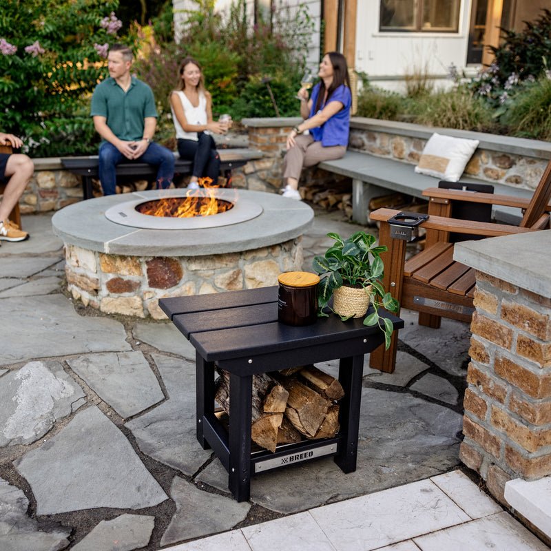 A group of friends hanging out around a Zentro firepit with X Series Furniture, featuring the X Series Side Table