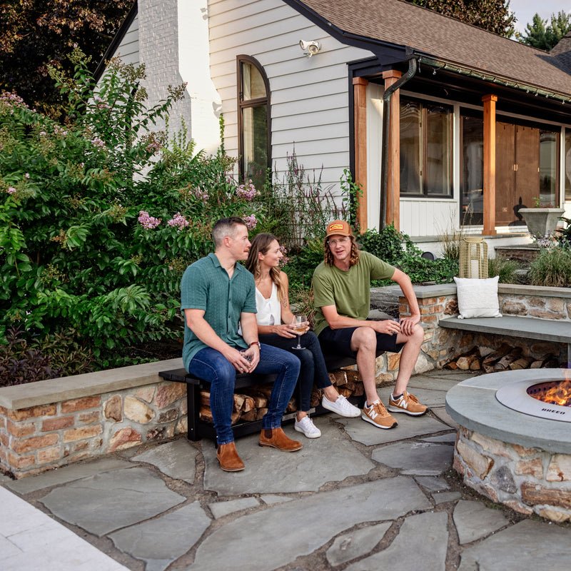 Three people sitting on the X Series bench around the Zentro firepit