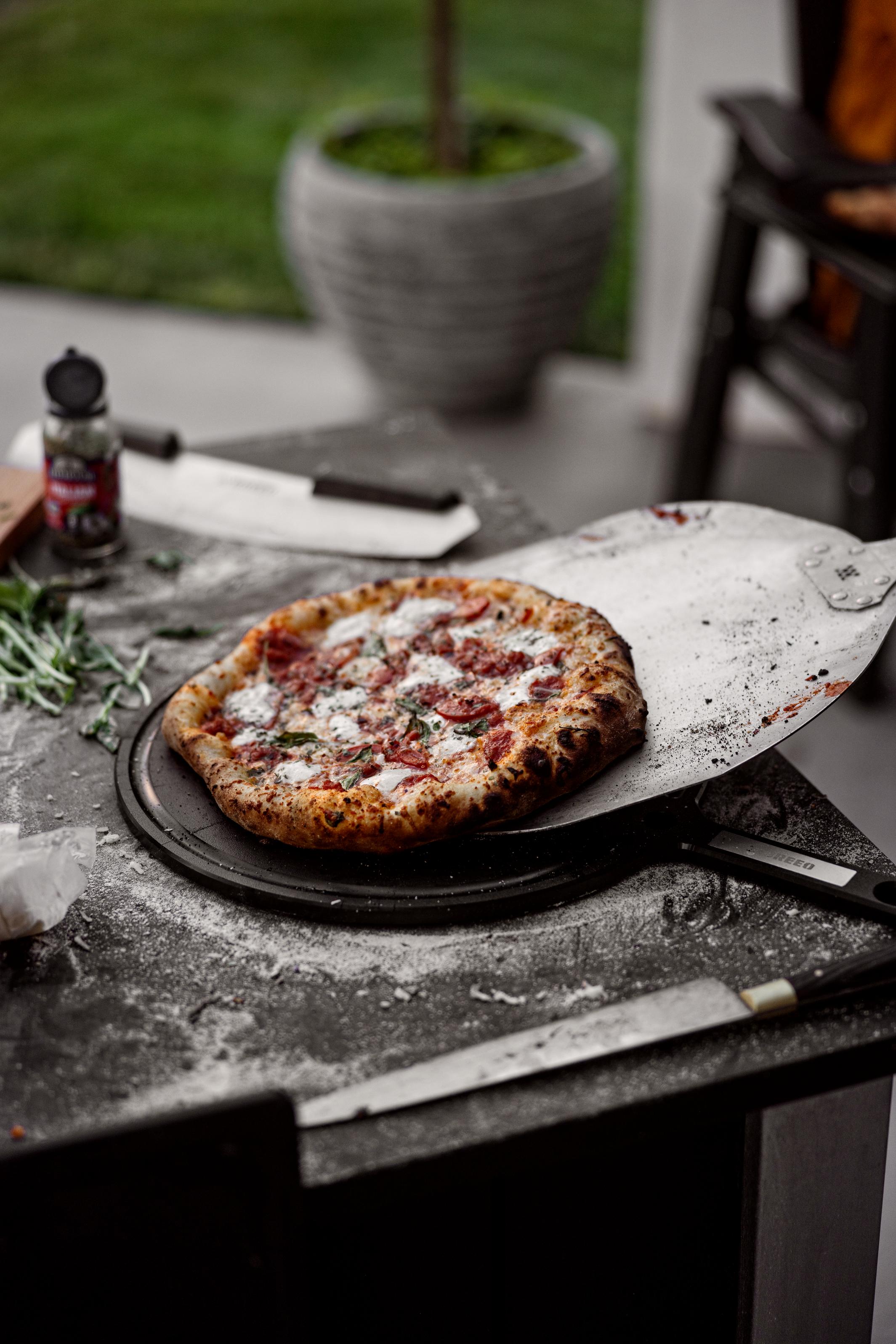 This is an image of pizza being transferred from a Pizza Peel to a Serving Board