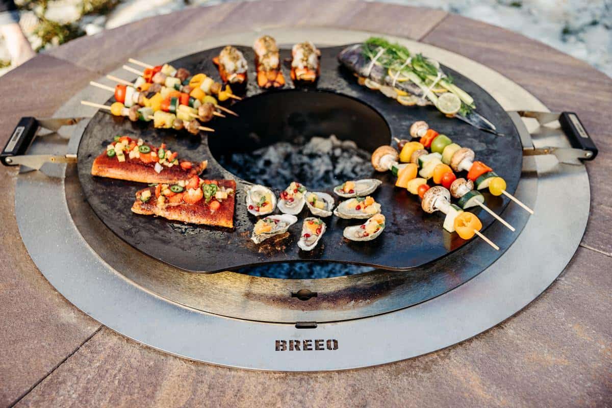 This is an image of the Breeo Searplate Griddle used to grill a variety of food over the fire