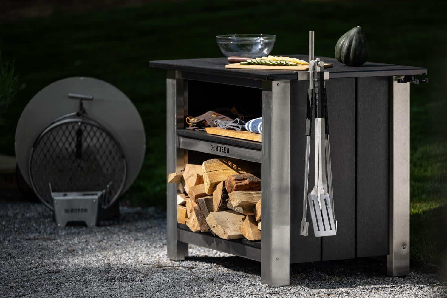 A Breeo X Series Table Setup with an OutRig Post and Grilling Tools hanging on the side.