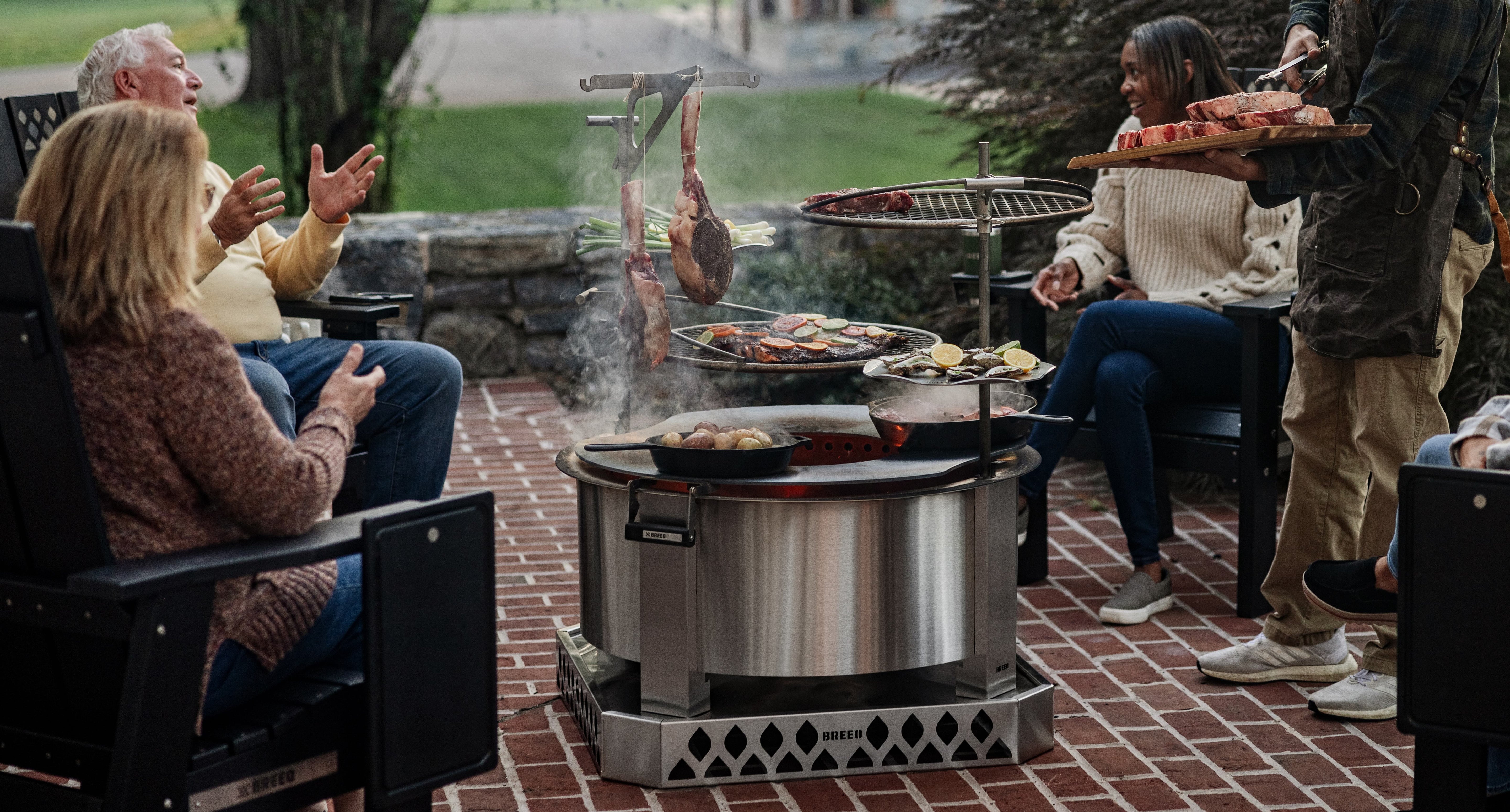 People gathered around a breeo fire pit grill in an outdoor setting