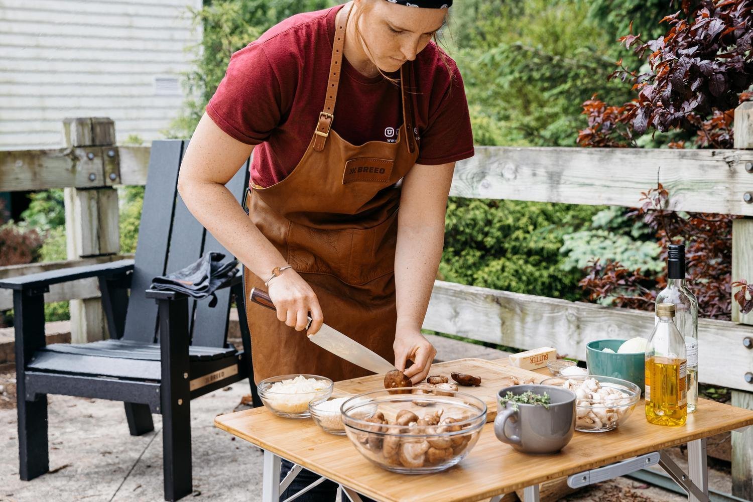 This is an image of a woman wearing the Breeo Leather Grilling Apron to prep food