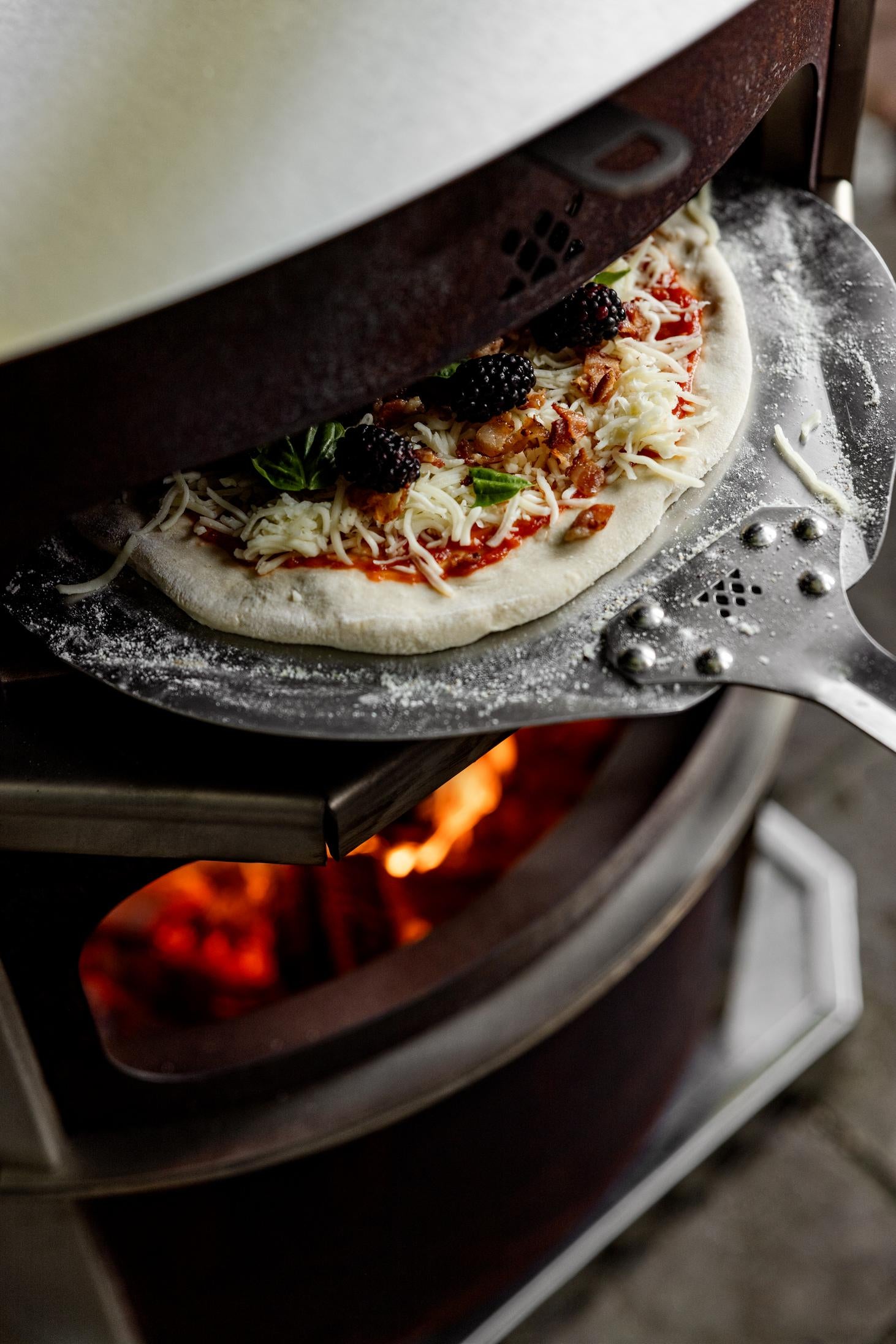 This is an image of putting pizza into a Pizza Oven using a Pizza Peel