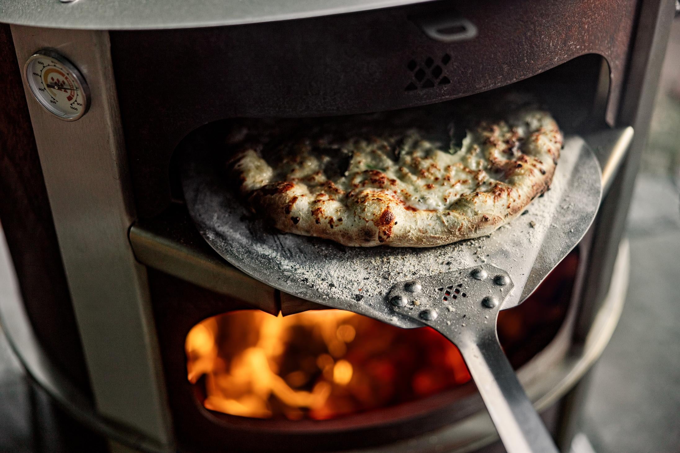 Removing a pizza from the Pizza Oven with a Breeo Pizza Peel