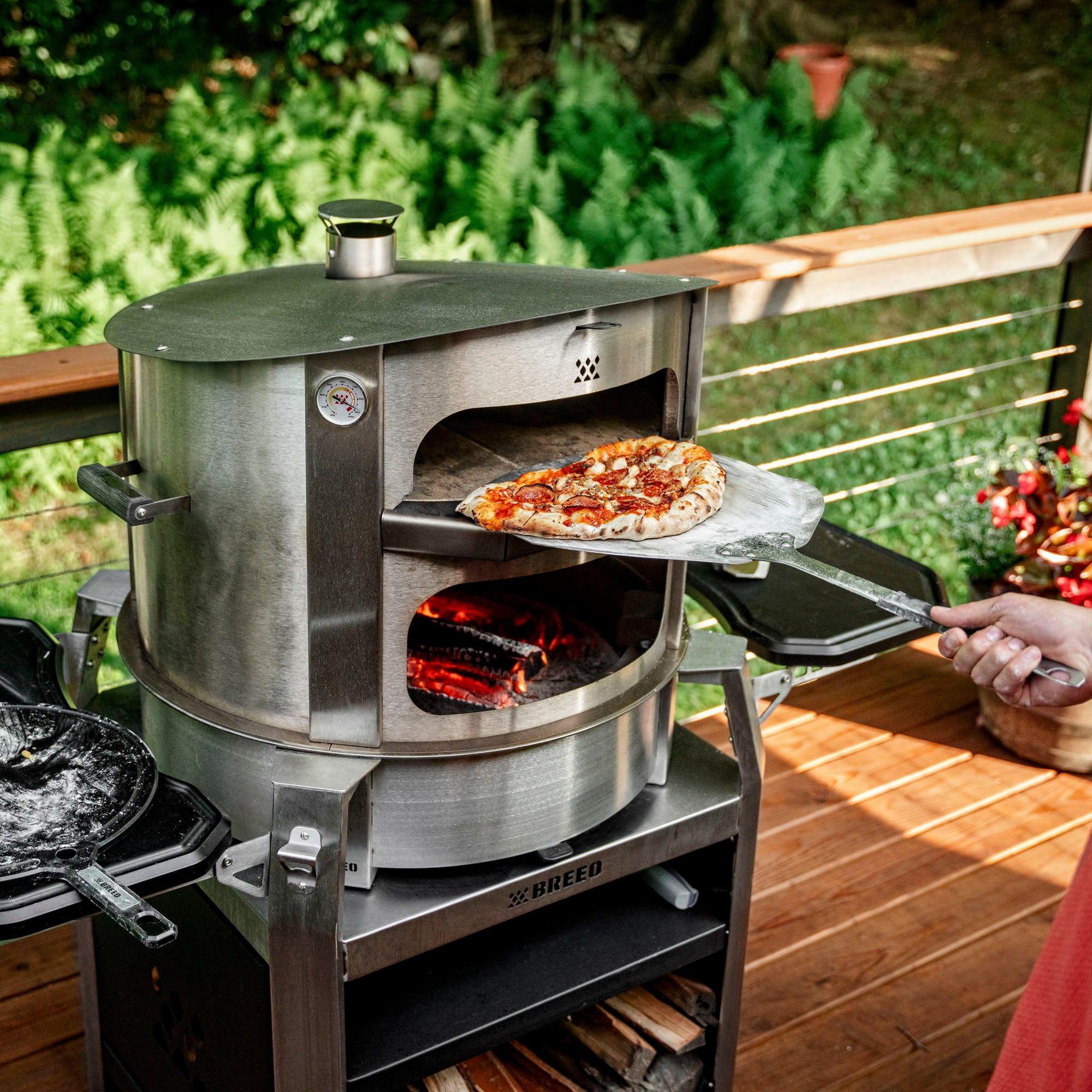 Breeo pizza oven with person cooking pizza