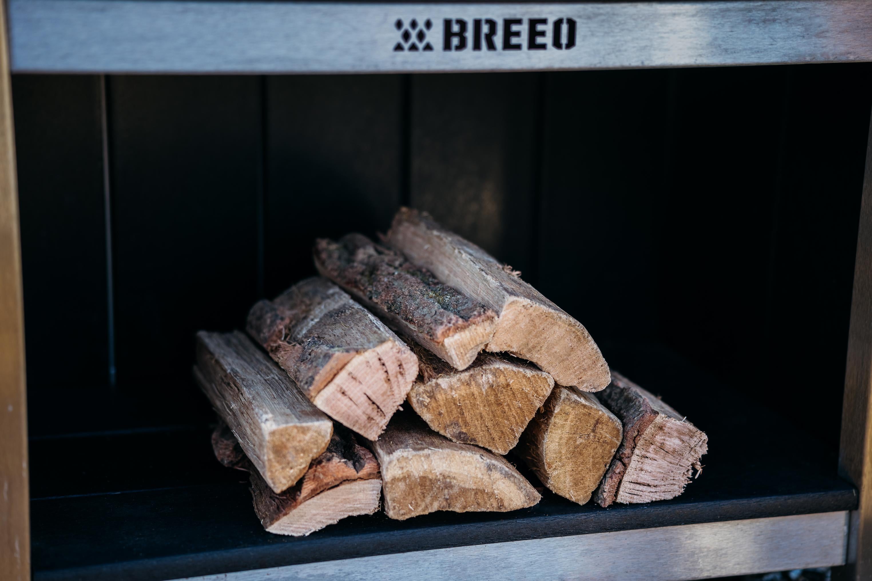 A stack of oak firewood stored in the Breeo X Series table