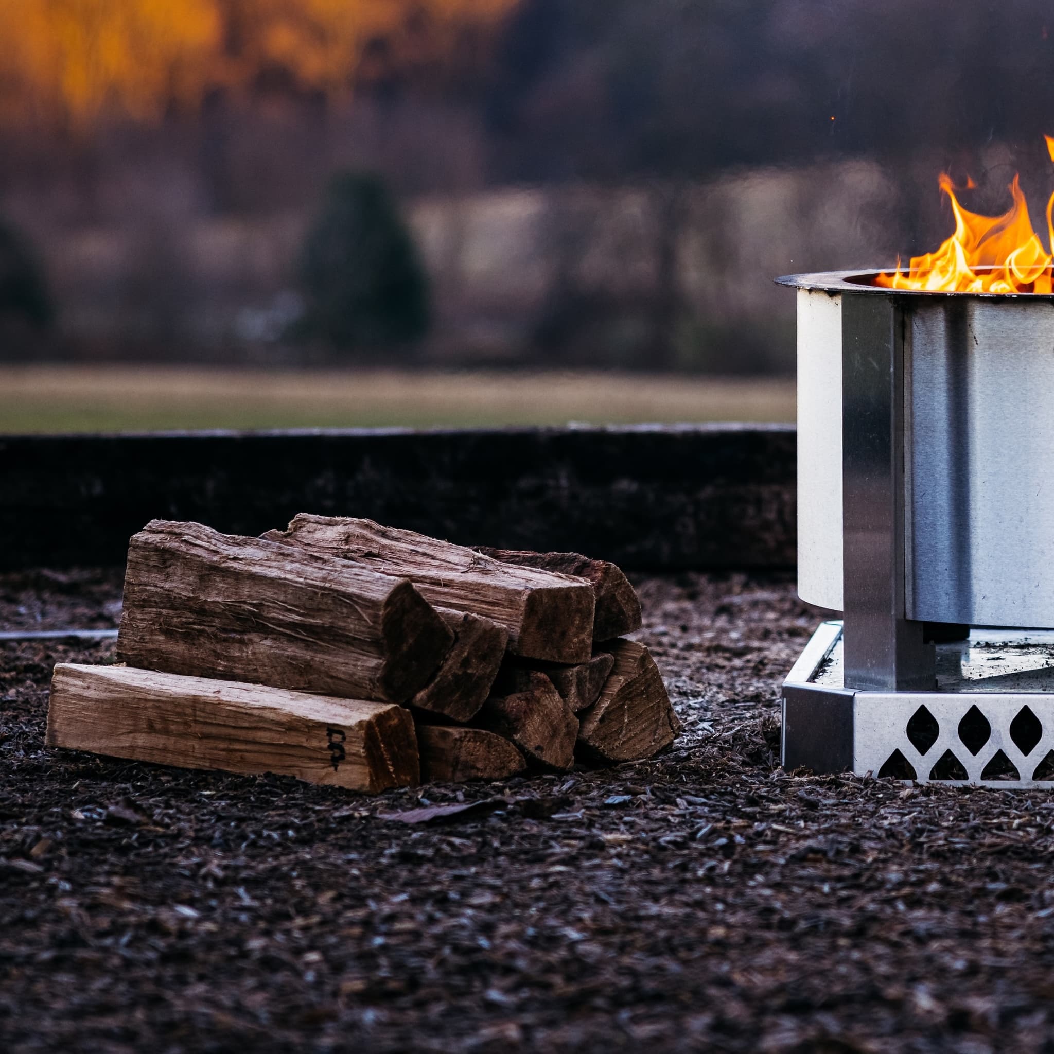 Oak firewood on a stack next to a Breeo firepit