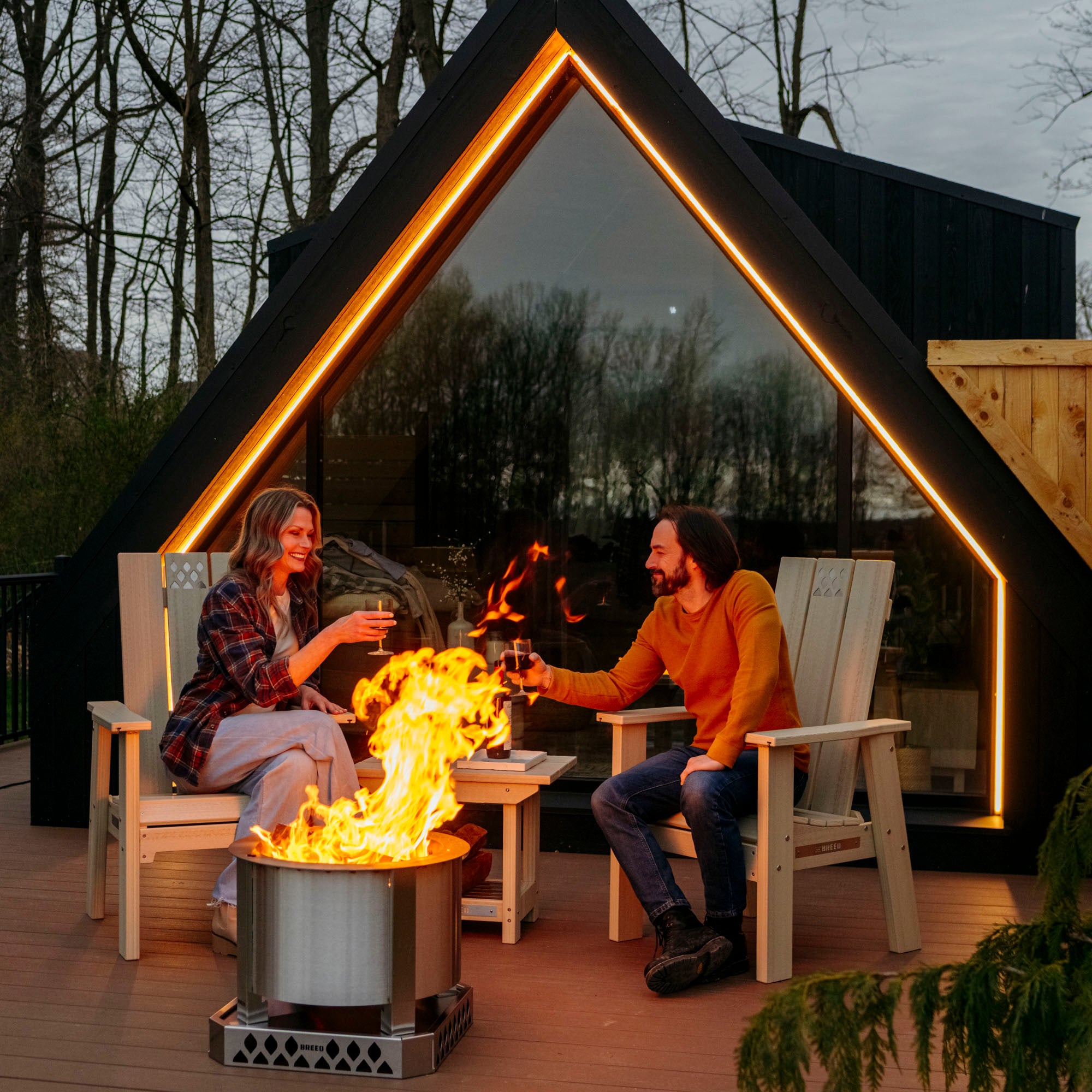 People outside enjoying drinks sitting in breeo chairs by a breeo smokeless firepit