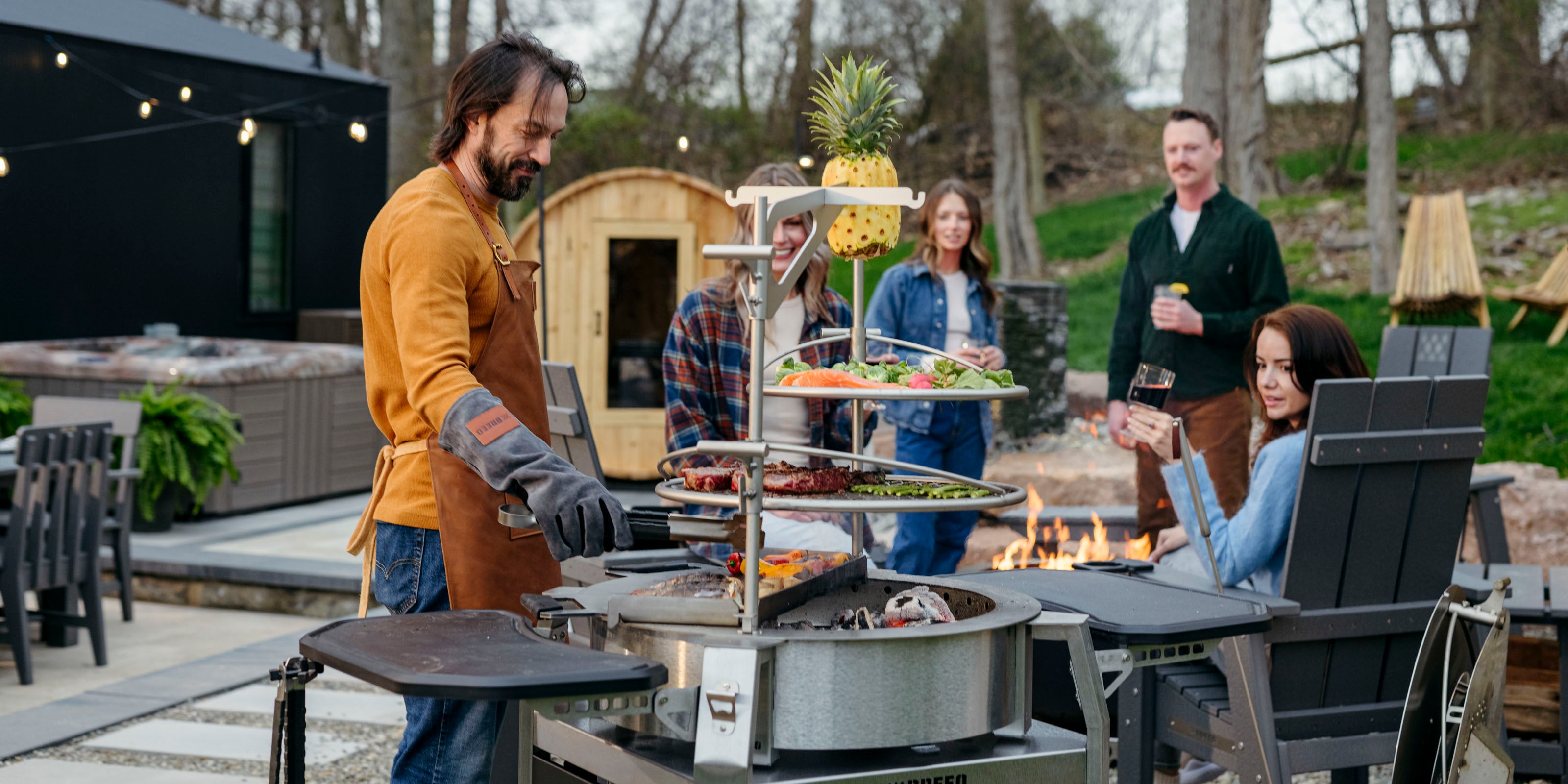 People cooking on multi tiered breeo smokeless firepit on patio outside