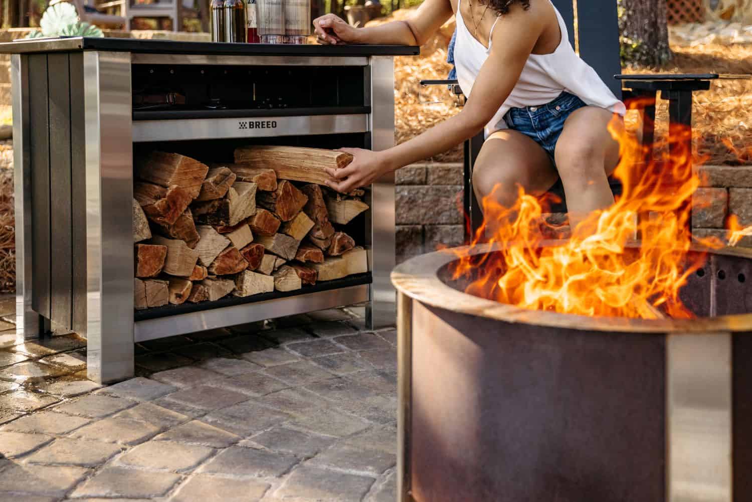 This is an image of a woman grabbing wood stored in the Breeo X Series Table