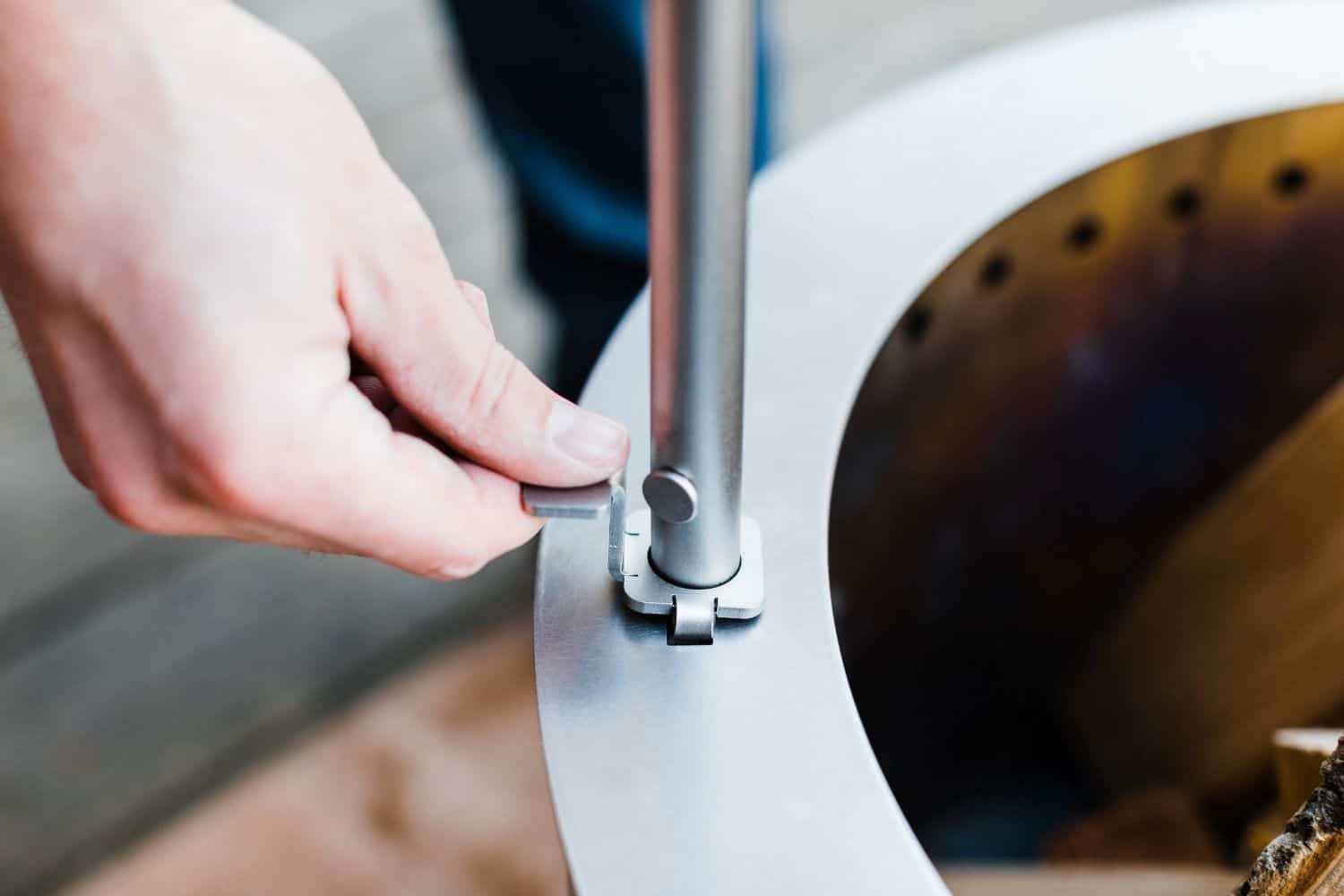 An image of a person attaching the Outpost Rod to an X Series firepit using the locking mechanism.