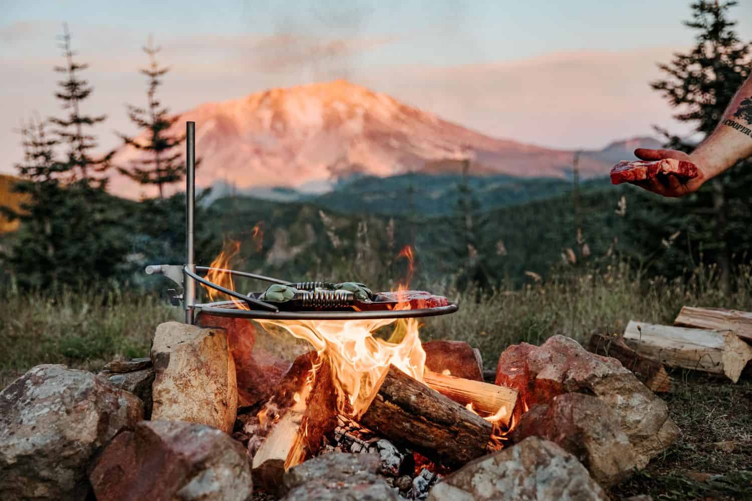 Grilling steaks over the fire on an Outpost Grill attached to the Anchorpoint.