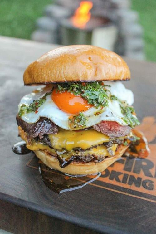 Chimichurri burger sits on a table with a Breeo burning in the background.