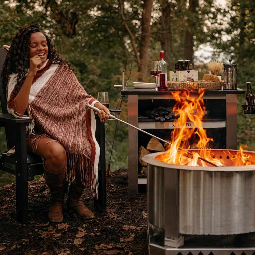 This is an image of a woman stoking the fire using a Breeo 304 Fire Poker