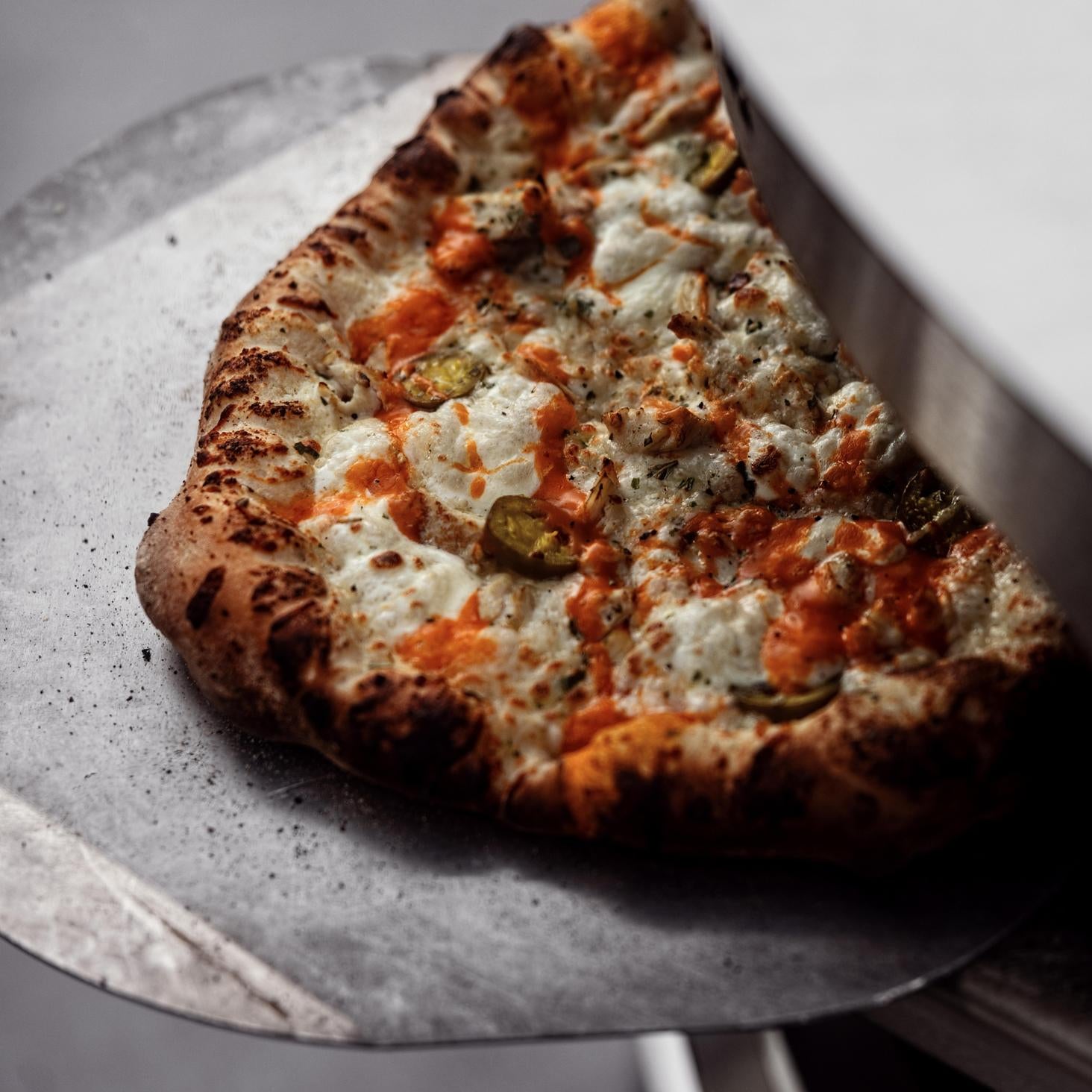 This is an image of a Breeo Pizza Peel Breeo Pizza Peel with a pizza coming out of the Pizza Oven