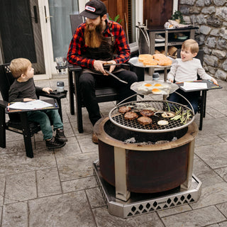 A man and his sons cooking burgers over the fire