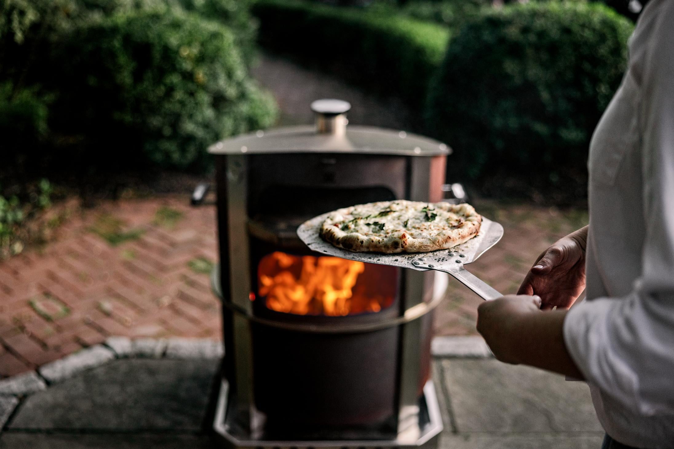 This is an image of someone removing the pizza from the pizza oven using a Pizza Peel