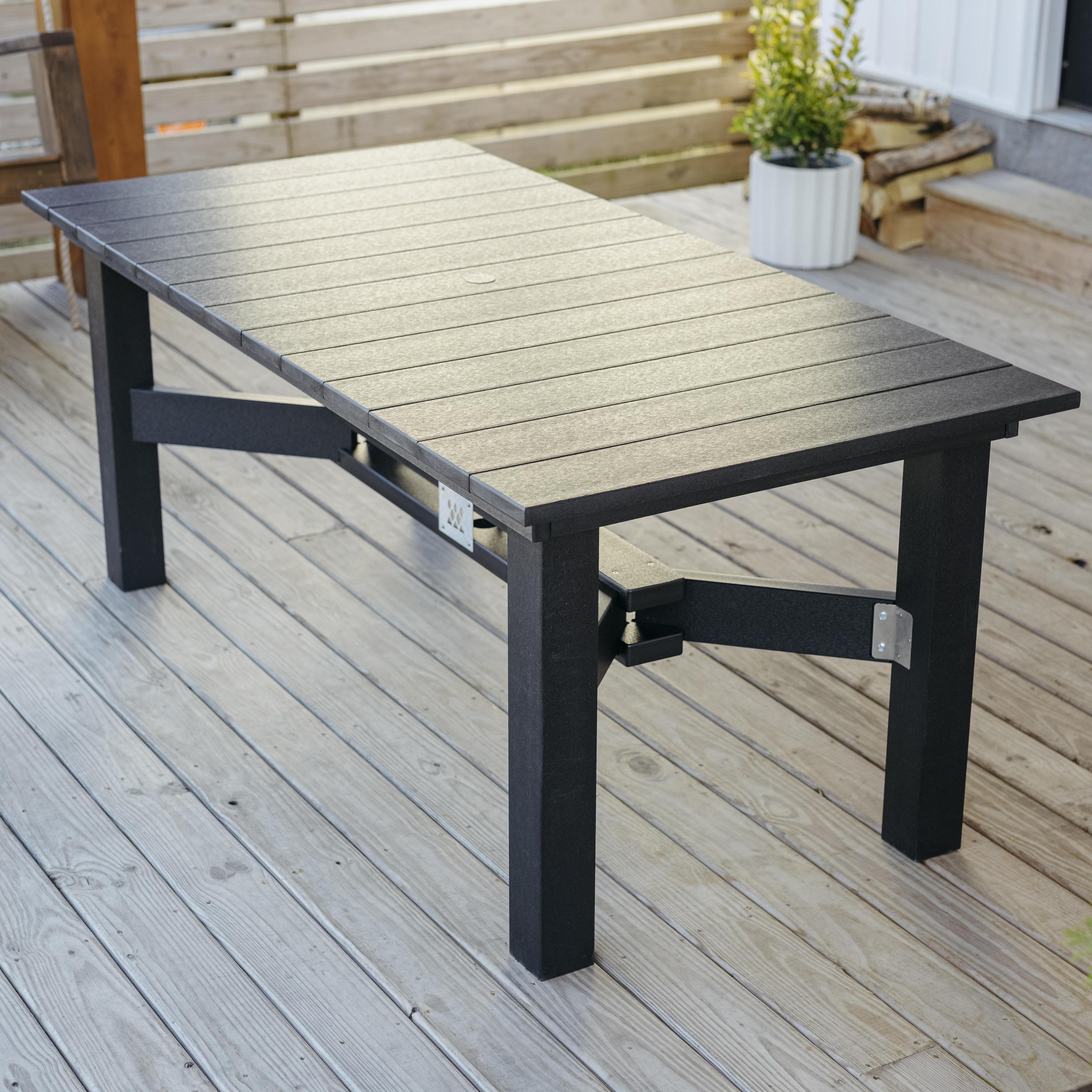 Breeo X Series dining table in black poly lumber with slatted top, positioned on a wood deck for outdoor entertaining