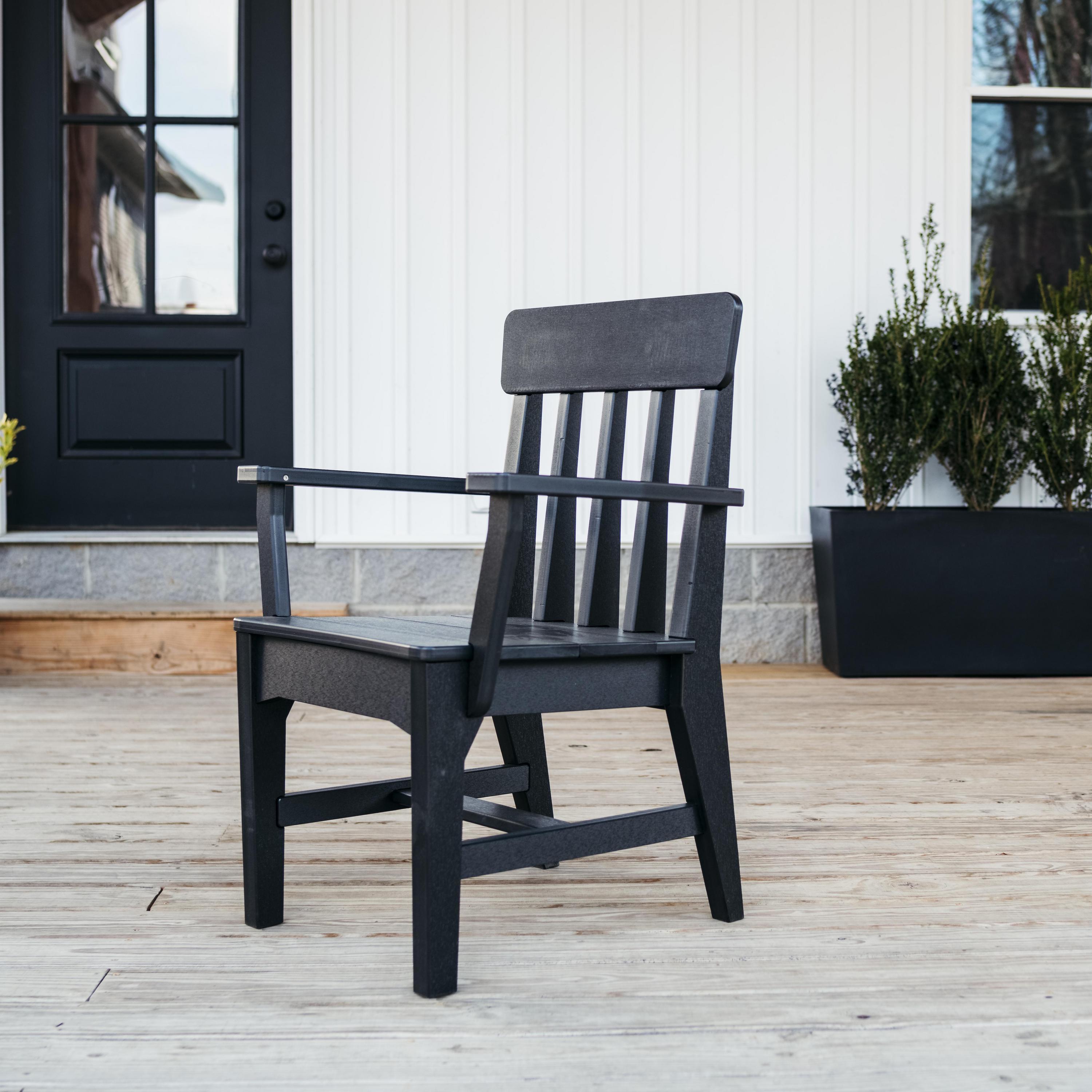 Breeo X Series dining arm chair in black poly lumber on a farmhouse-style wood deck with black door and vertical siding