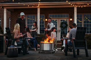 A group of friends sit around an X24 fire pit in Breeo X Series chairs.